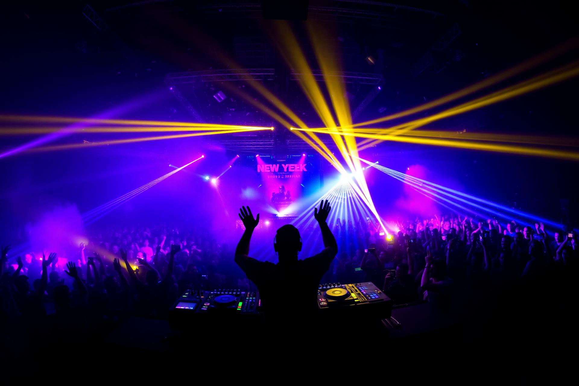 DJ performing at packed venue with neon lights